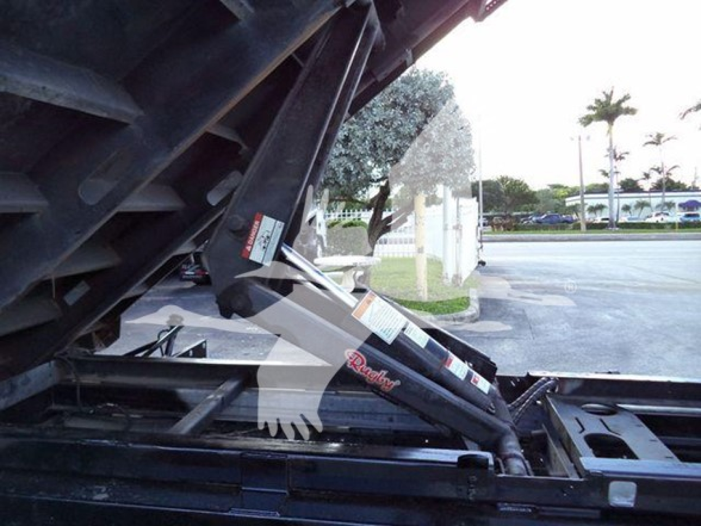 Ford E450 dump truck side view showing hydraulic ram and bed linkage with Warn winch label visible.