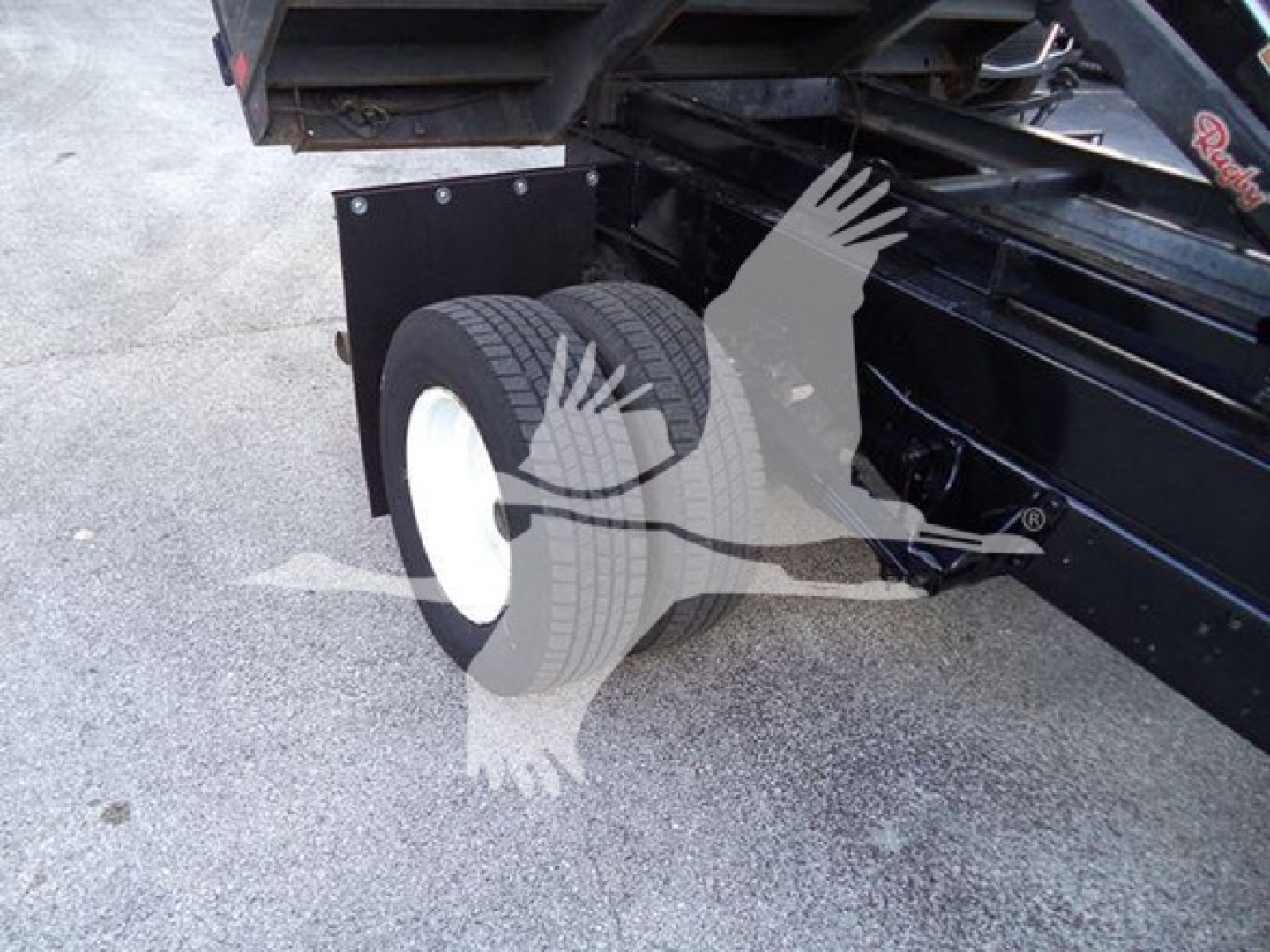 Ford E-Series F450 dump truck rear wheel assembly and undercarriage, showing dual rear wheels and black chassis with white wheel rims.