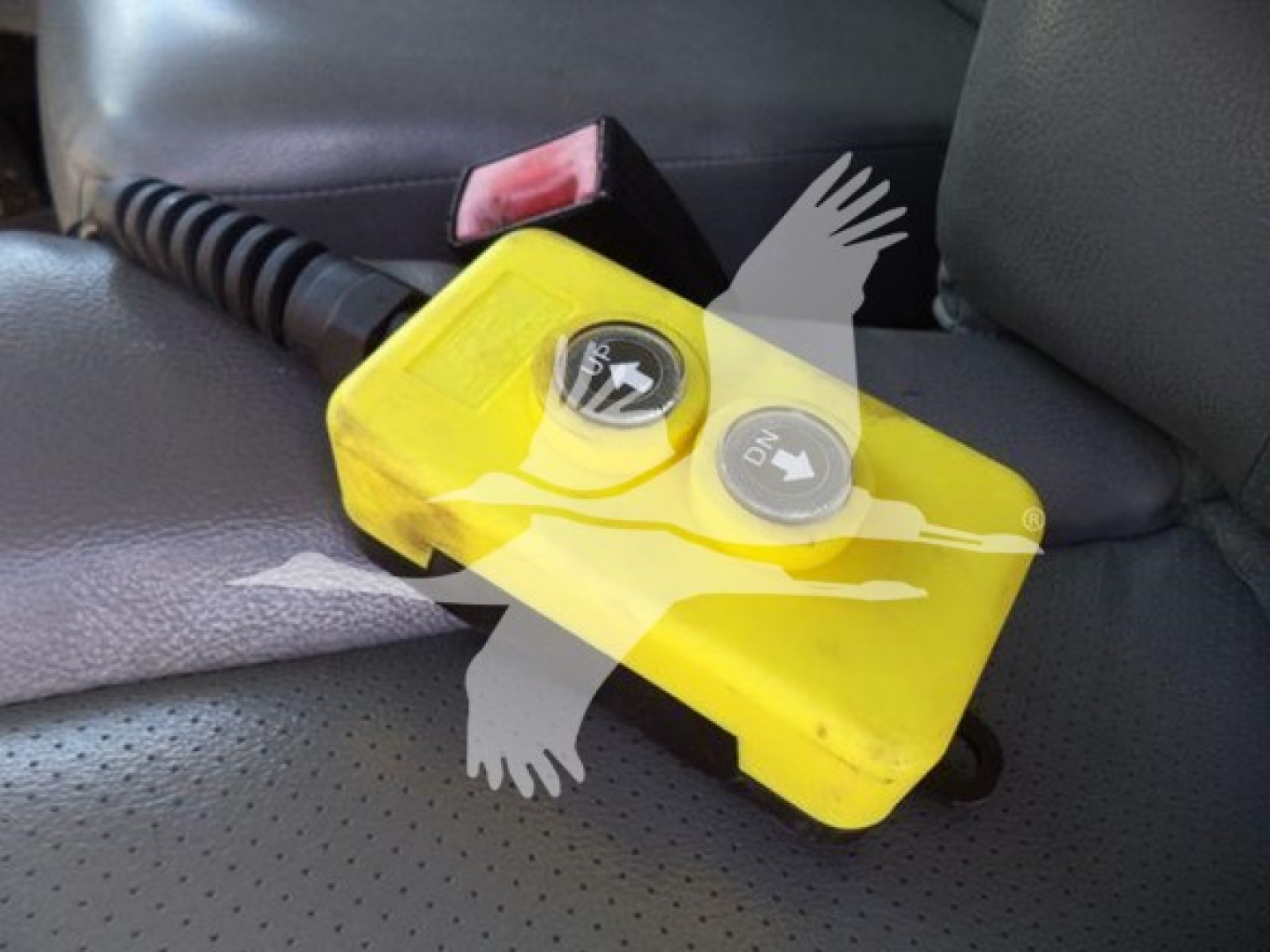 Vehicle interior showing yellow opaque reservoir with two caps and a coiled cord; likely a fluid reservoir for a Ford E-450 dumping truck.