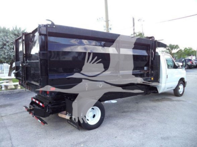 Dump truck with black dump bed and white cab, side view showing rear hydraulic dump mechanism and wheel. No visible text legible.