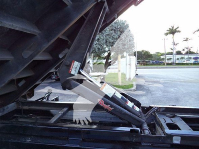 Ford E450 dump truck side view showing hydraulic ram and bed linkage with Warn winch label visible.