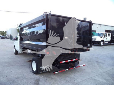 Dump truck with black dump body and white cab showing rear view; no text clearly legible except a small sticker and reflective tape on rear bumper.