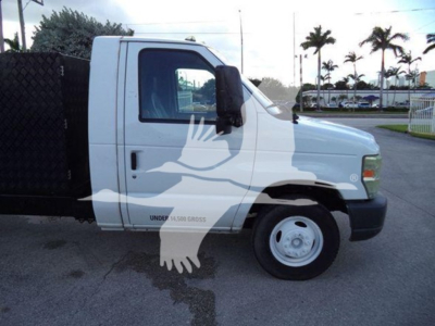 Ford E-Series cutaway truck side view showing single cab, white, with black dump bed and front wheel visible.