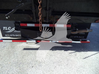Ford E-450 dump truck undercarriage showing chain and rear hitch with TLC equipment branding.