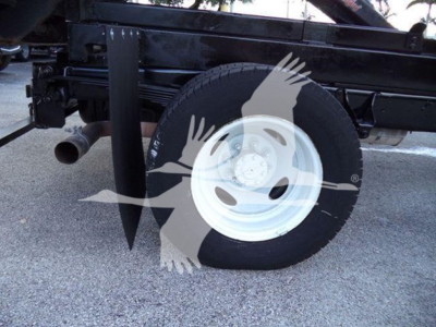 Ford E450 dump truck side view showing a white wheel rim, tire, and undercarriage components.