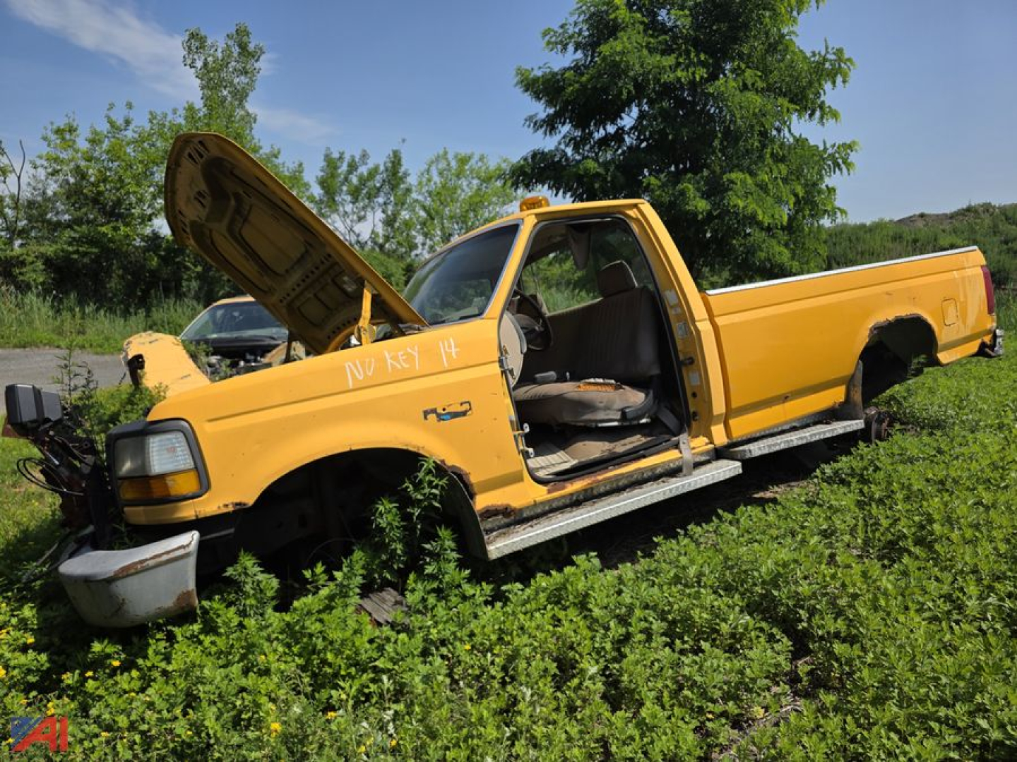 1993 Ford F-350 pickup truck with yellow paint, hood open, exposed engine bay, front bumper detached, doors open, side steps, in grassy lot.