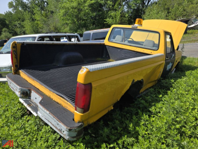 1993 Ford F-350 pickup truck with open bed in a field; yellow body, rear tailgate down, spare tail light, open hood and side step.