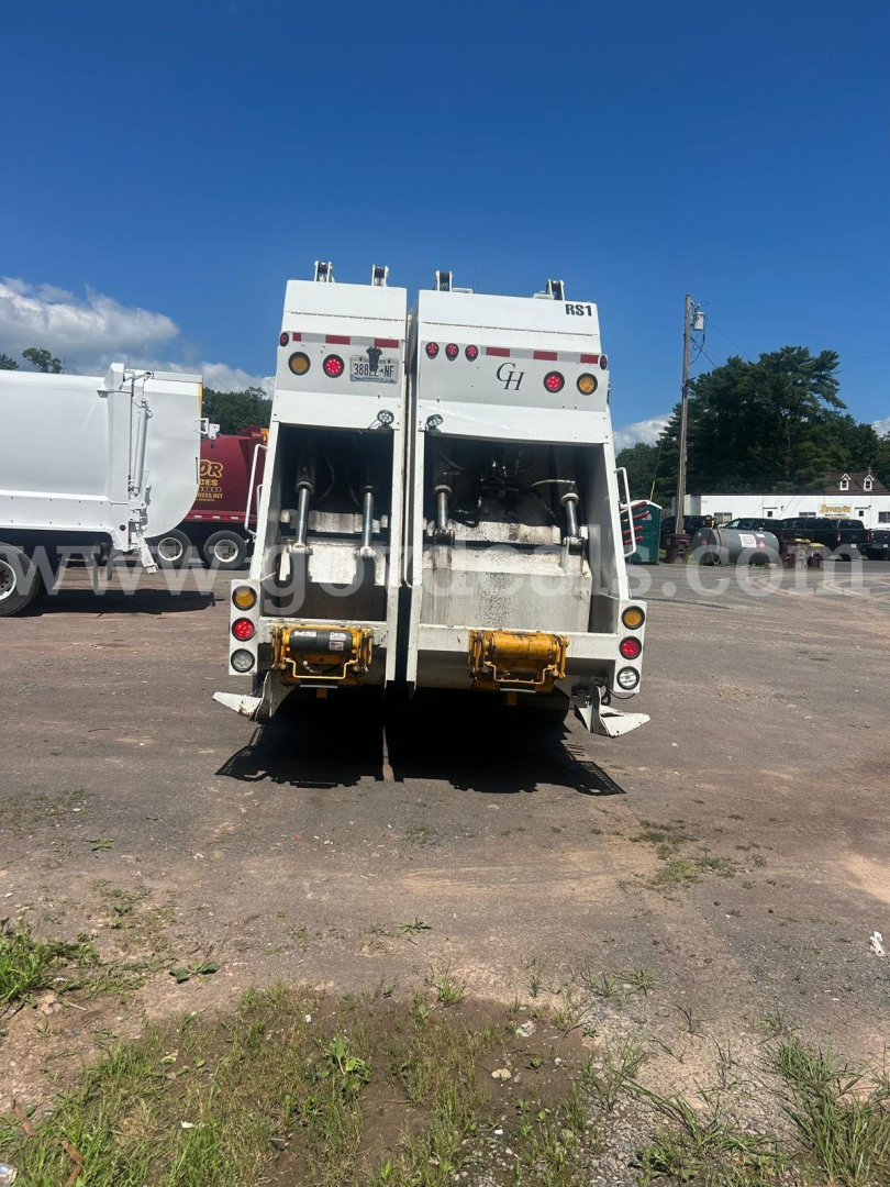 Rear view of a white Autocar XPeditor dump truck with dual hydraulic arms, taillights, and hydraulic components visible; VIN and stock number not shown in image.