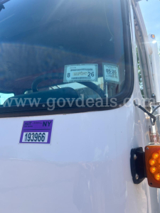 Truck windshield with inspection stickers and a purple HUT sticker on the white cab of a 2010 Autocar Xpeditor.