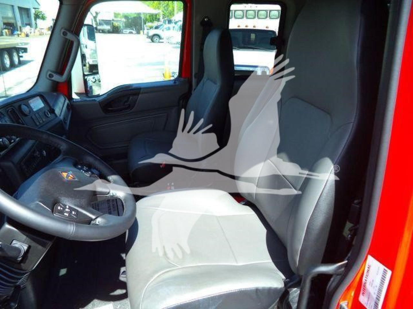 Truck cab interior of a new 2027 International MV rollback truck showing driver and passenger seats, steering wheel, dashboard with controls.
