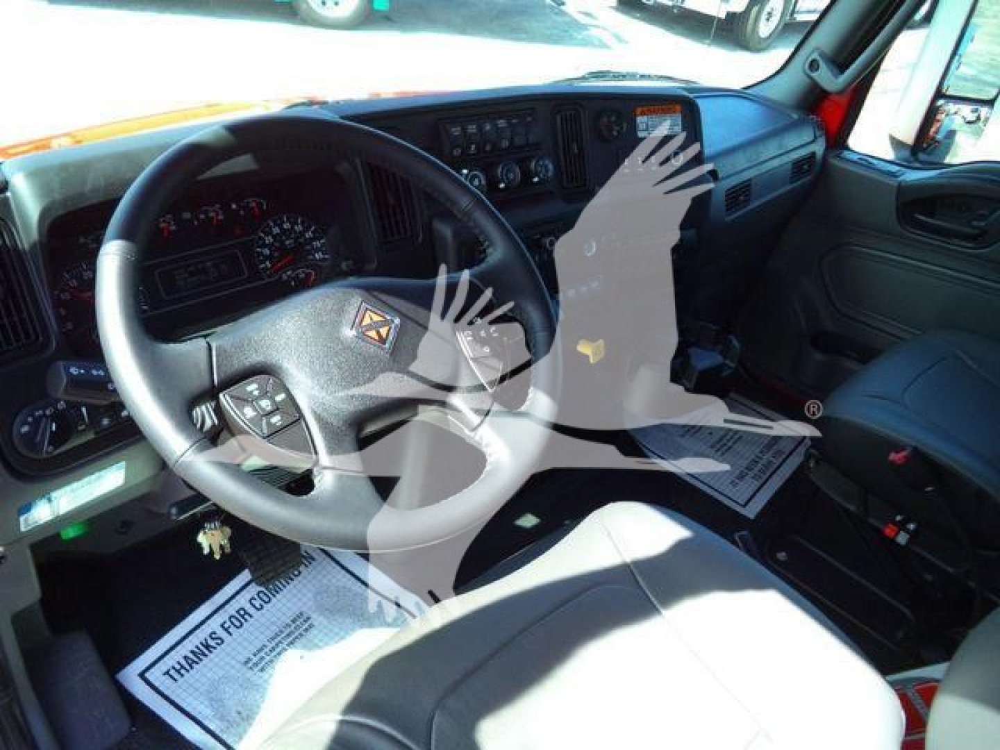 Interior view of a 2027 International MV truck cab showing steering wheel with logo and dashboard gauges.