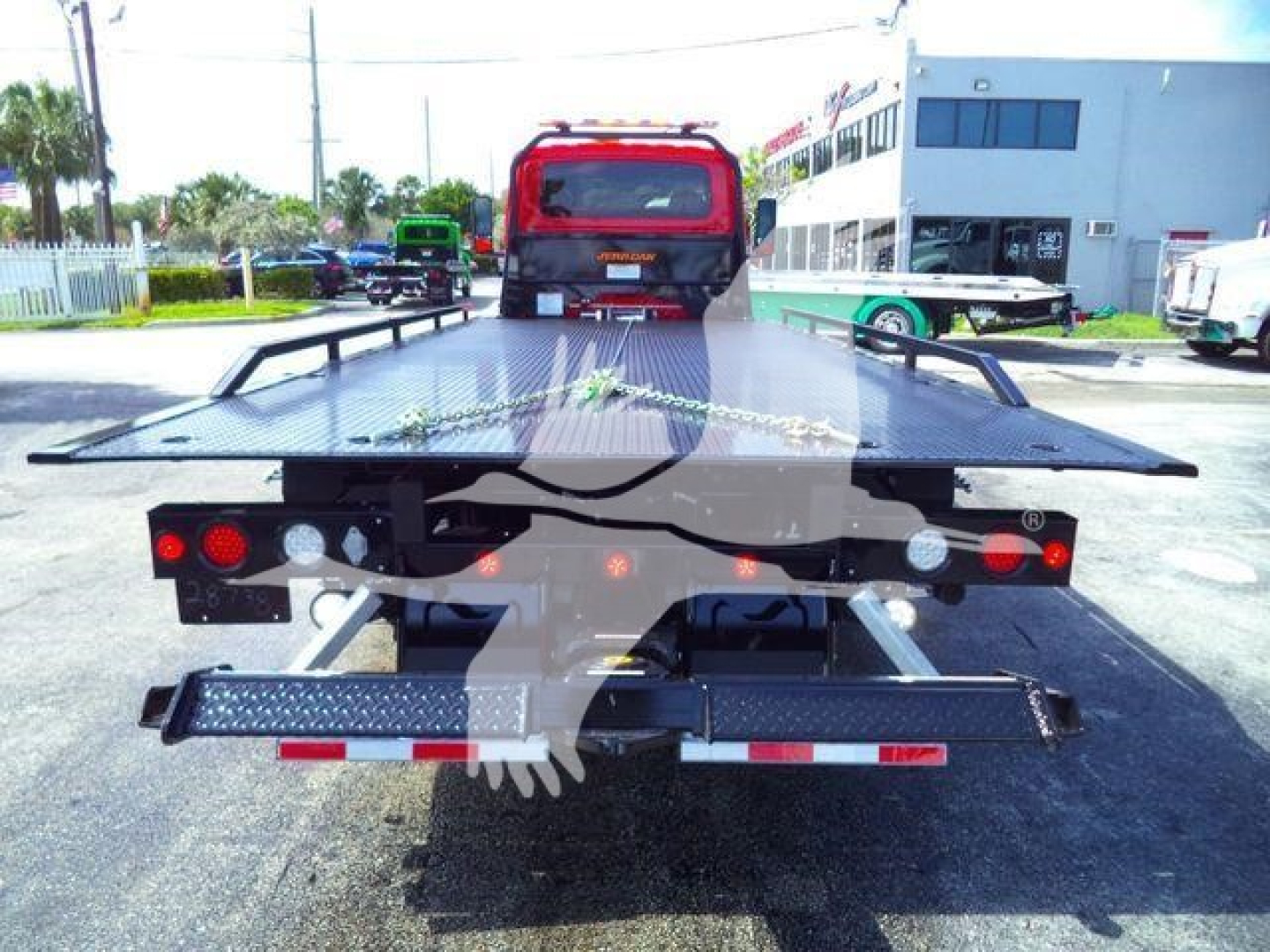 Tow truck rollback bed with diamond plate platform and rear bumper, seen from the rear showing taillights and modular hinge assemblies.