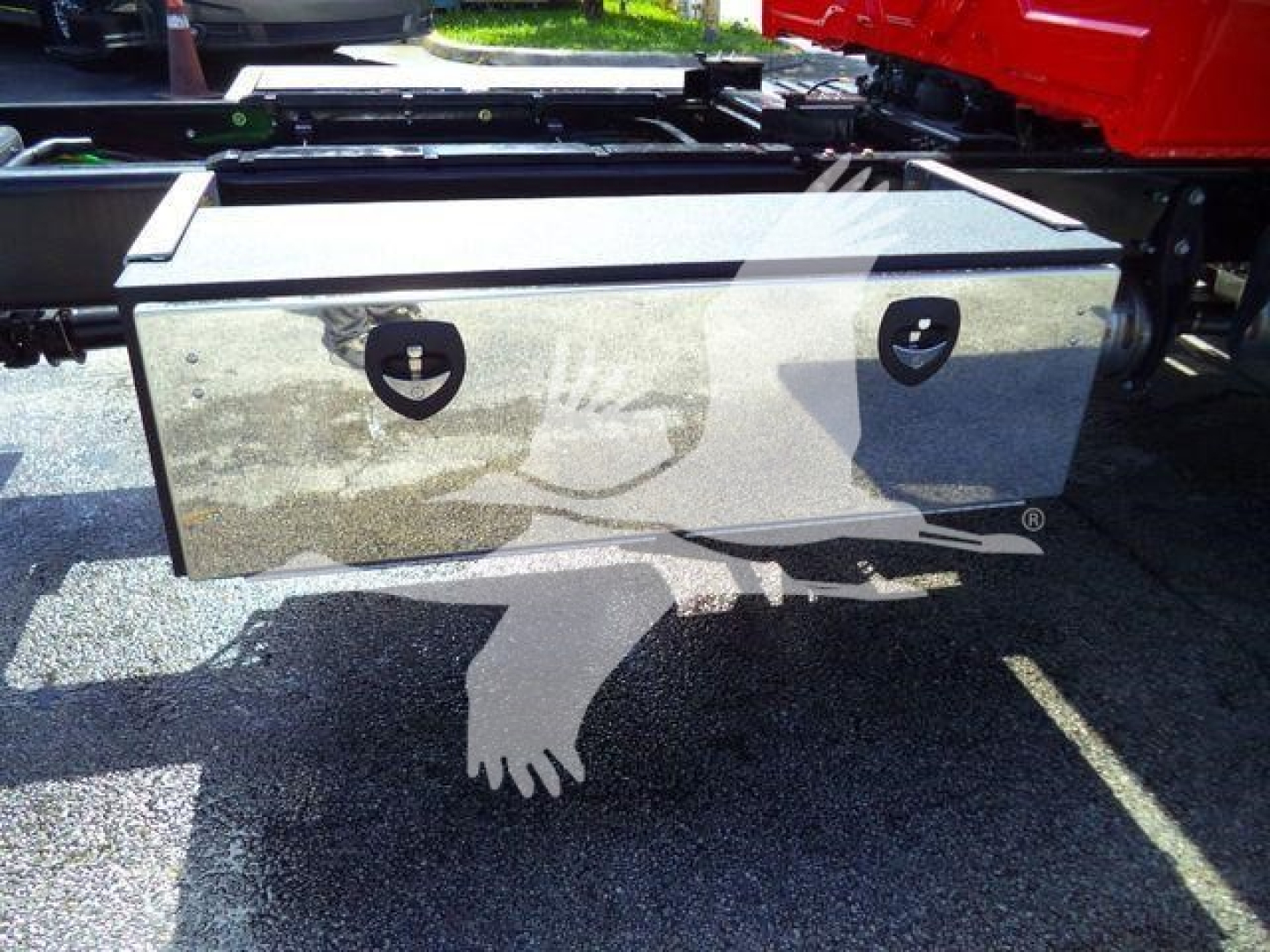 Storage box mounted under a rollback truck with metal exterior and two circular latches.