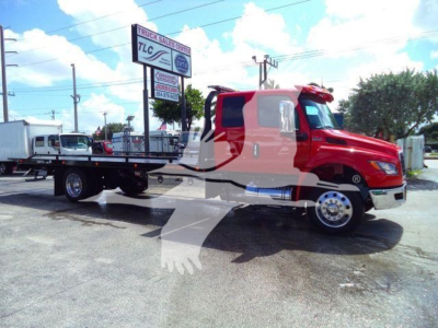 Red International MV rollback truck with flatbed on a lot, showing MV607RED stock number in background.