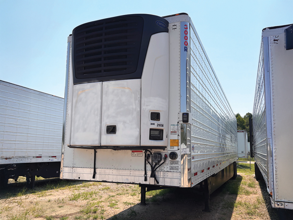 Rear view of a refrigerated trailer with a vertical Thermo King unit, white and silver with dark front grill; a tall blue side sticker reads '3000R'; other trailers are visible on both sides.