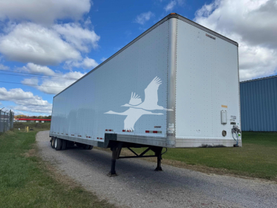 Manac 48' sheet and post drop trailer in side view with landing gear, white with bird logo; visible VIN/stock info not legible; cloudy sky