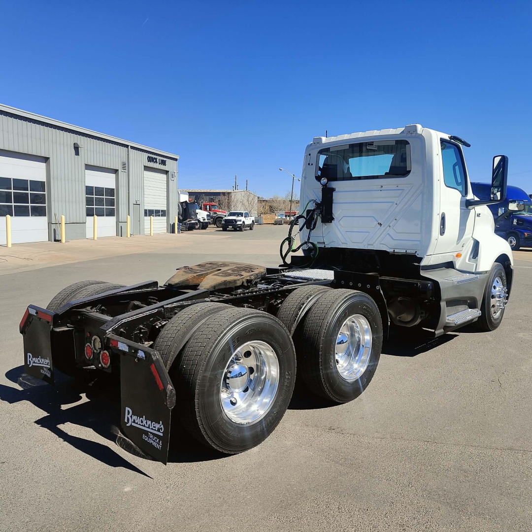 International LT truck chassis rear view showing dual rear axles and mud flaps with brand text