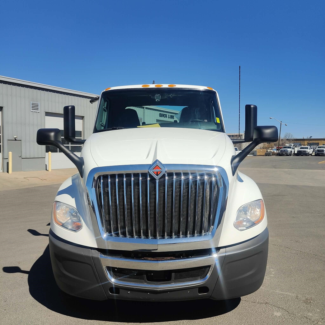 Front view of a white 2021 International LT conventional daycab truck showing large chrome grille, headlights, black bumper, mirrors, and amber marker lights on the cab roof.