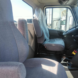 Truck cab interior with driver and passenger seats visible; plastic covers on seats; steering wheel and dashboard on right; no external text visible.