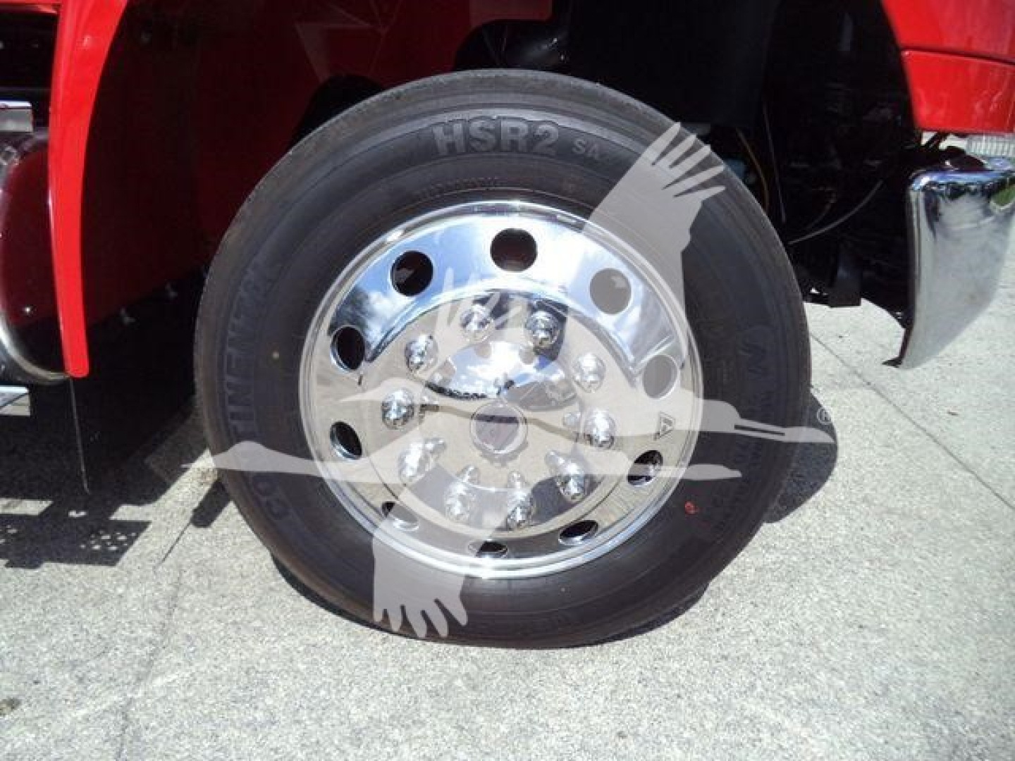 Wheel and tire on a truck with chrome hub and lug nuts, showing HSR2 tire and red fender in background.