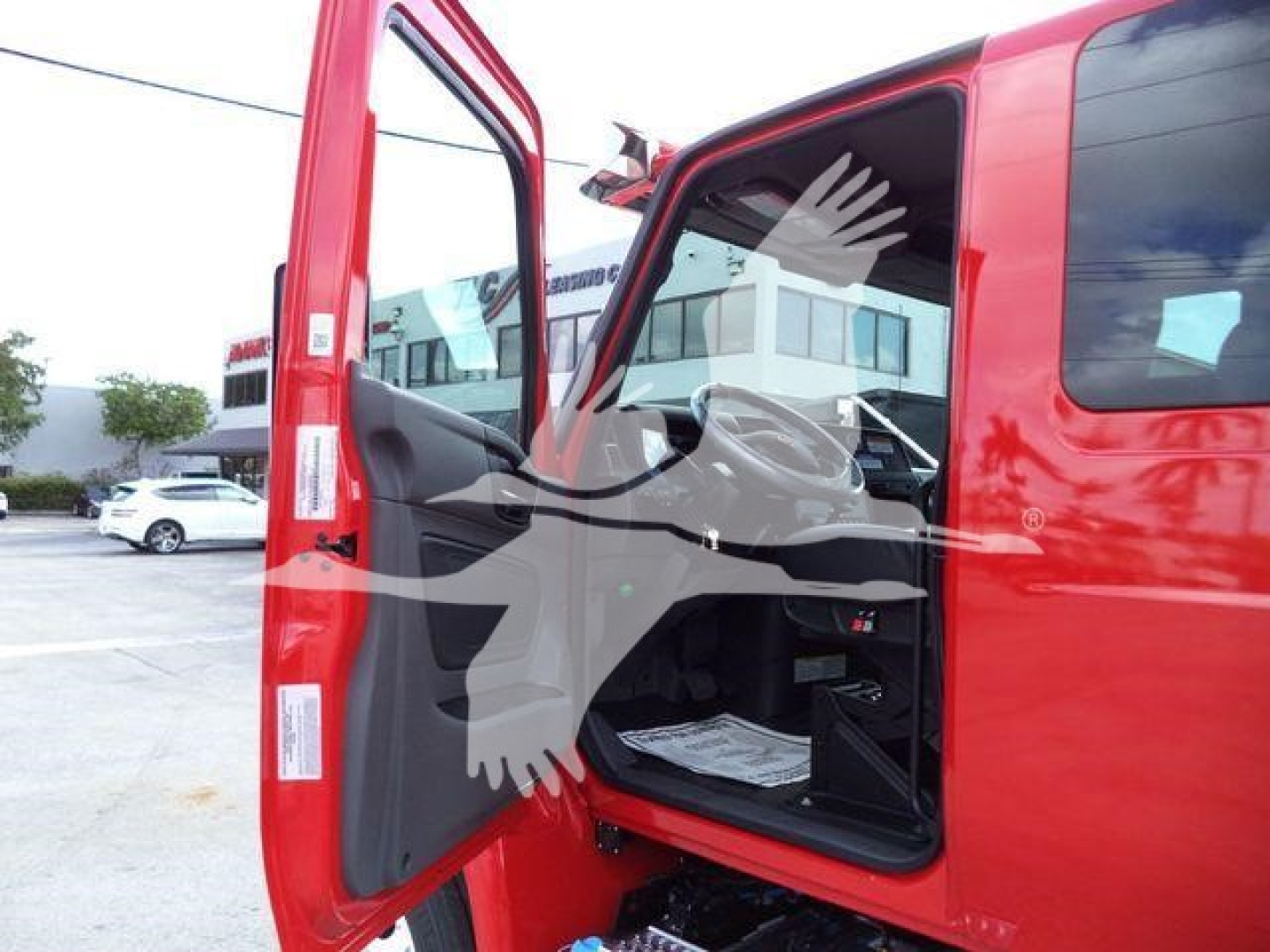 Truck cab interior with open driver door showing steering wheel, dashboard, and papers on floor; red exterior; Rollback truck category.