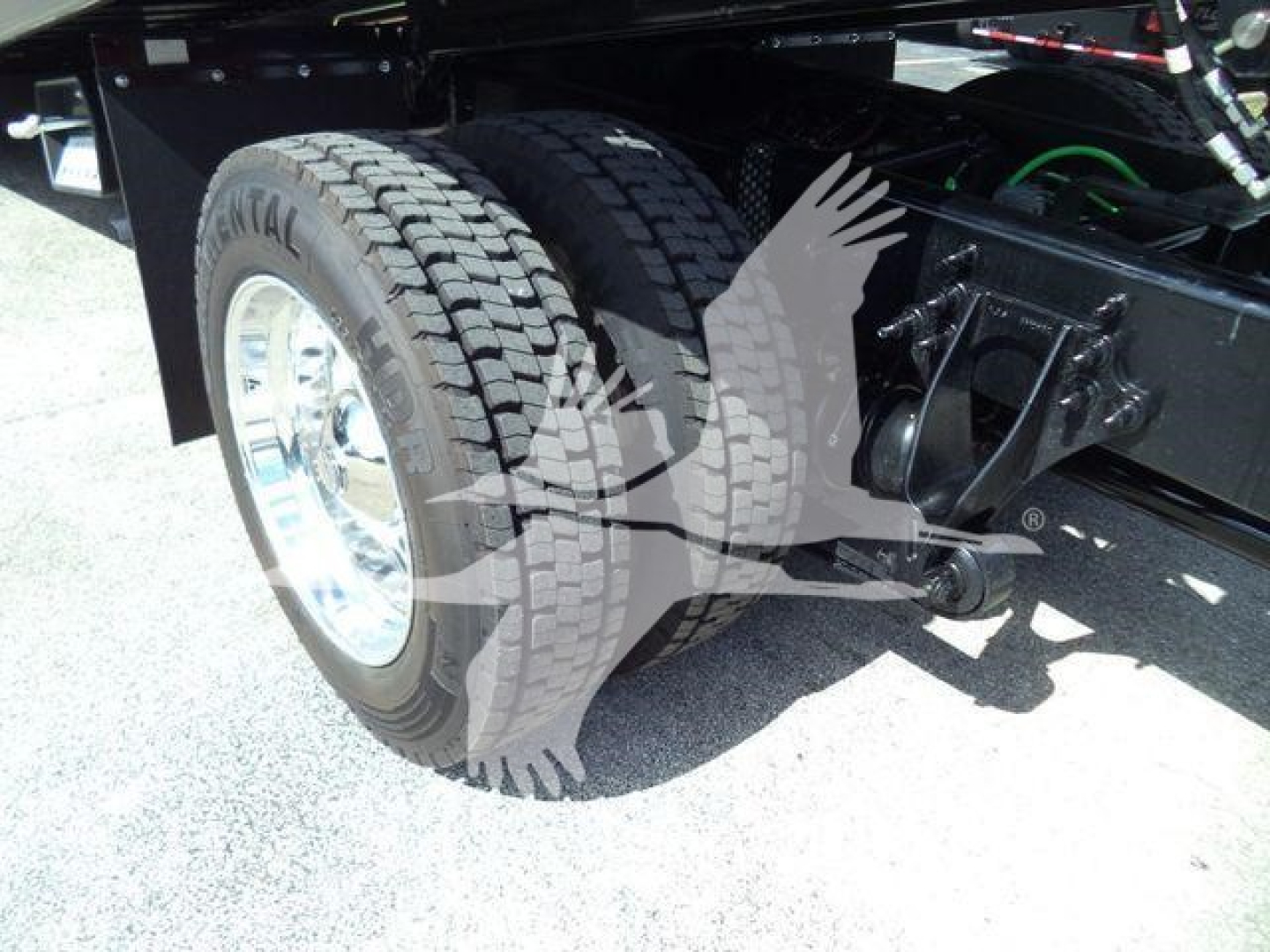 Truck rear dual tires and suspension components visible under frame.