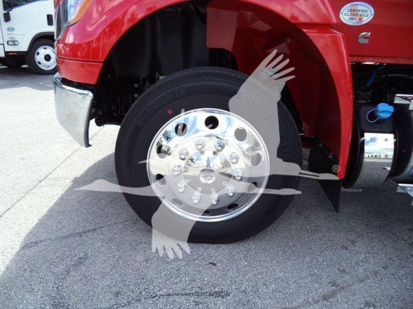 Truck wheel and front fender showing polished chrome wheel and red body of 2027 International MV rollback truck.