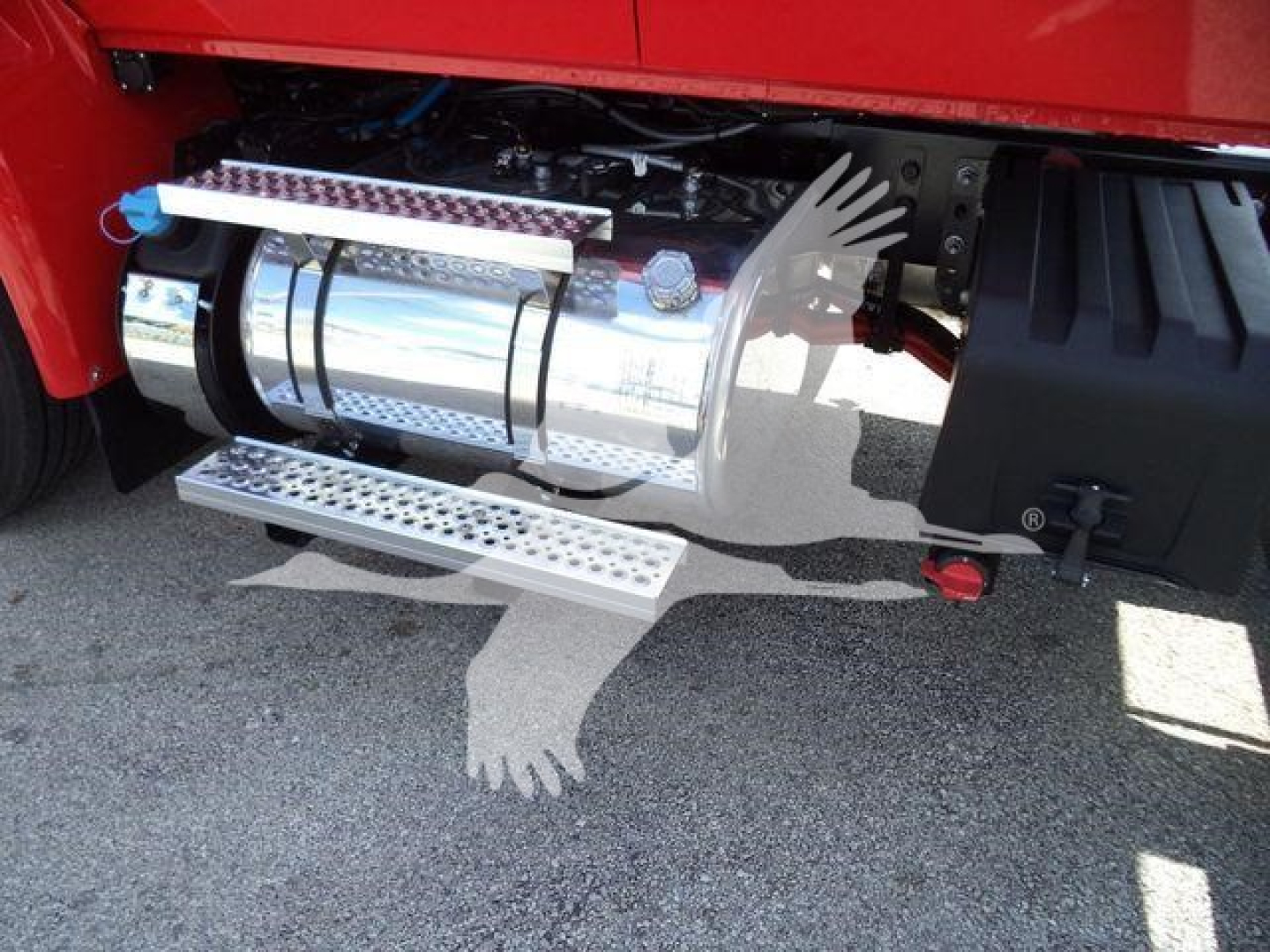 Tractor-trailer side showing polished chrome exhaust/power unit with metal steps and black fender, part of a new 2027 International MV rollback truck.