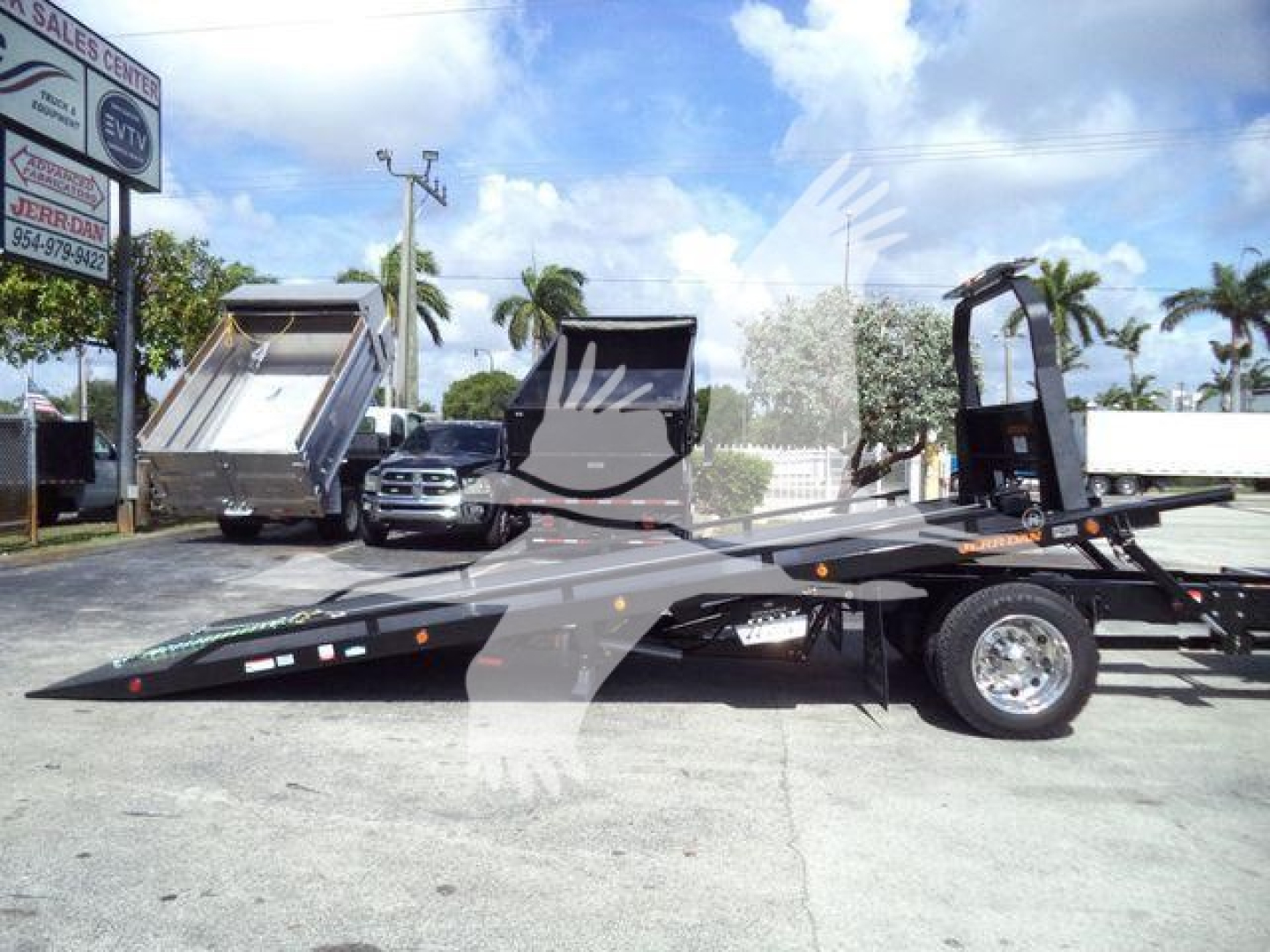 Flatbed rollback tow truck with hydraulic tilt bed and wheel-lift; text on equipment not clearly legible from distance.