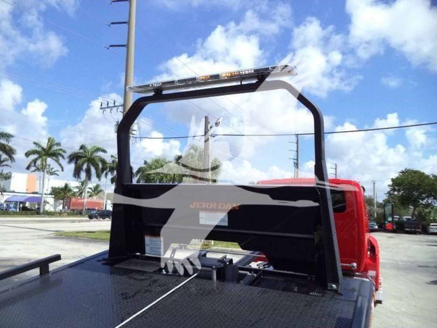 Truck bed and overhead protective frame on a 2027 International MV rollback truck showing rear cab, flatbed with safety rails and light bar.