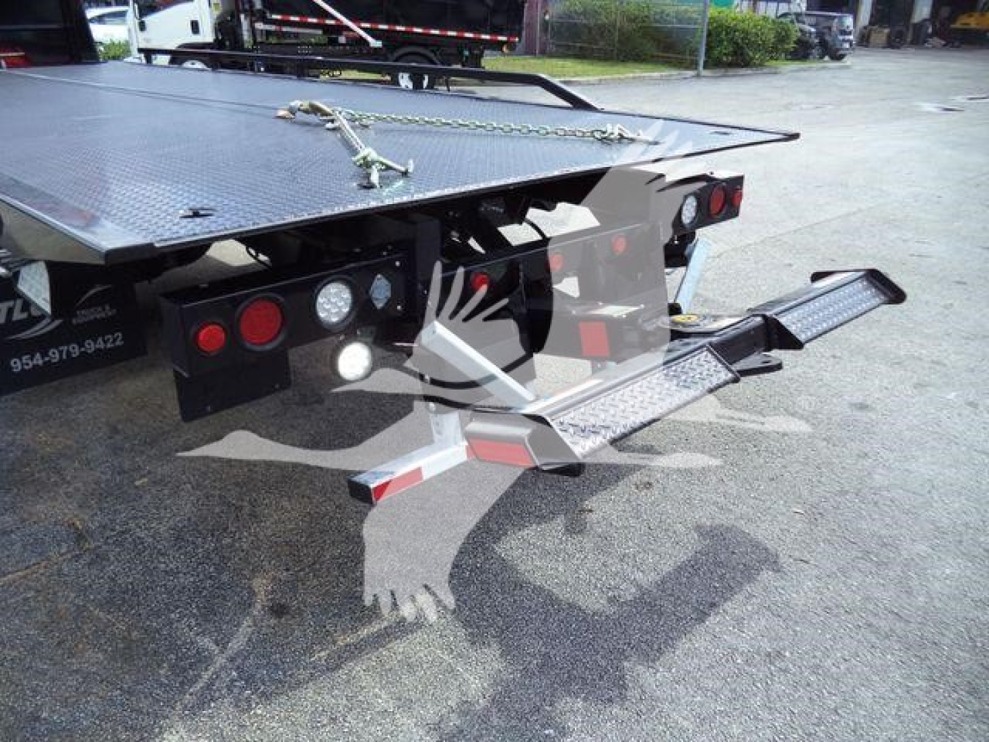 Truck bed with hydraulic rollback equipment and steps showing rear taillights and platform plate.