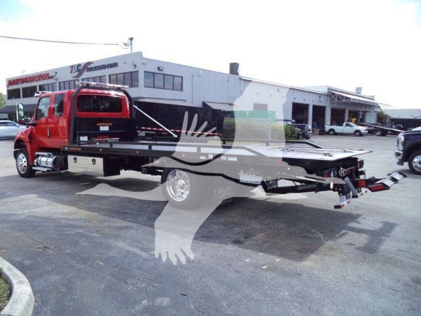 Truck with a rollback bed and red cab in an outdoor lot, International MV model on sale.