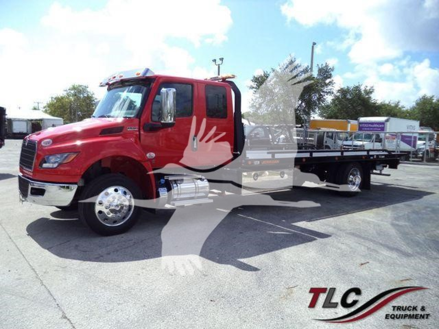 Truck image showing a red International MV rollback truck with a long flatbed, side mirrors, and chrome wheels. No visible license plate or numbers.