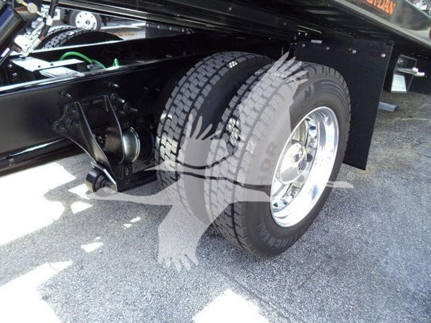 Truck wheel and suspension undercarriage showing dual rear axles and frame portion of a 2027 International MV rollback truck.