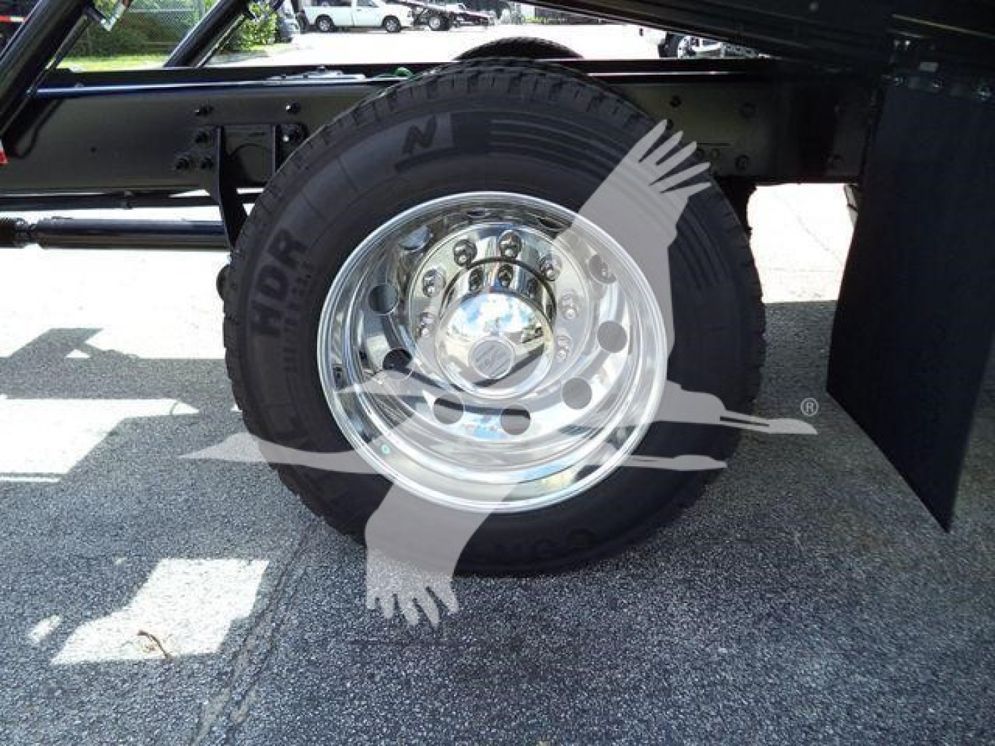 Wheel and tire assembly of a new International MV rollback truck showing chrome hubcap and black tire.