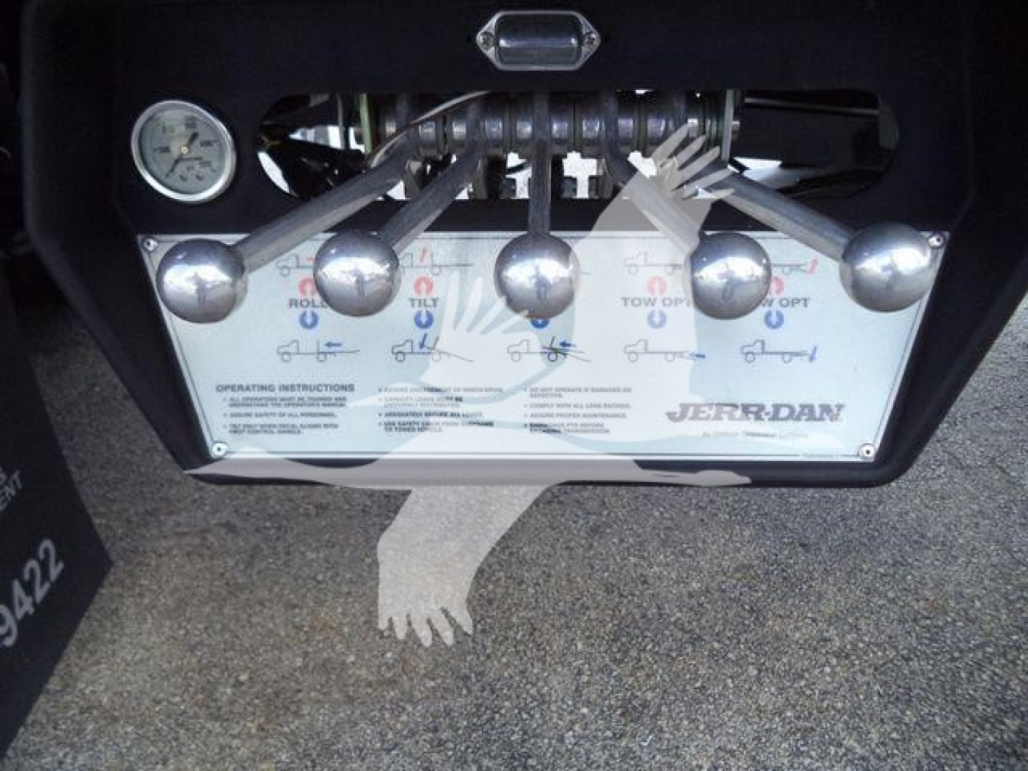 Panel with controls and gauge on a Jerr-Dan rollback tow truck, showing operating instructions and levers labeled with icons.