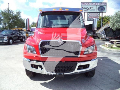 Front view of a red 2027 International MV truck in a dealership lot, showing the grille, headlights, chrome bumper, and side mirrors.