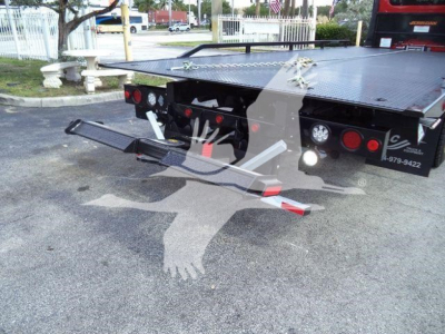 Truck bed of a rollback tow truck showing rear platform and safety chains
