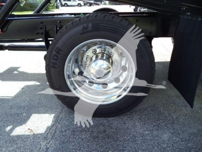 Wheel and tire assembly of a new International MV rollback truck showing chrome hubcap and black tire.