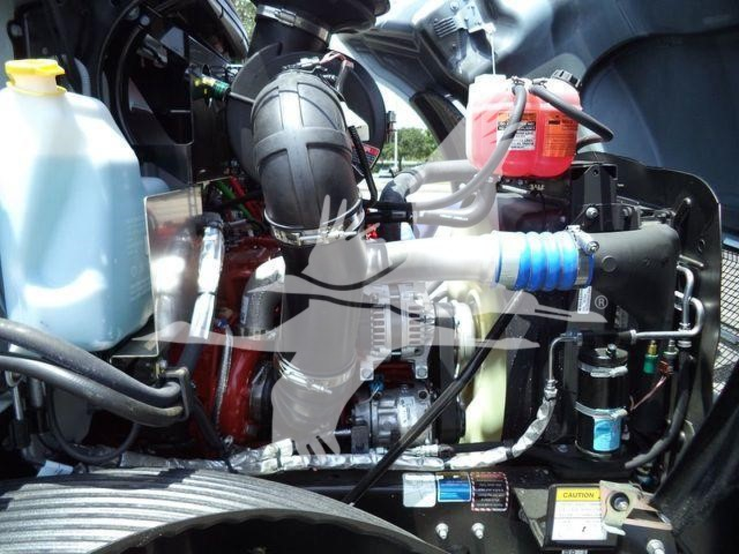 MD6 engine bay showing coolant reservoir, hoses, and components in a Mack truck.