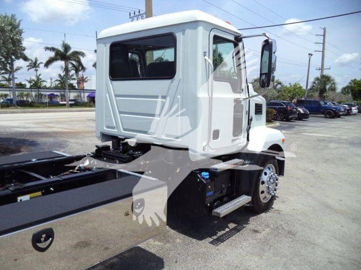 Truck cab and chassis of a new 2025 Mack MD6 rollback truck showing the crew cab, side step, fuel tank, and wheel with chrome rim.