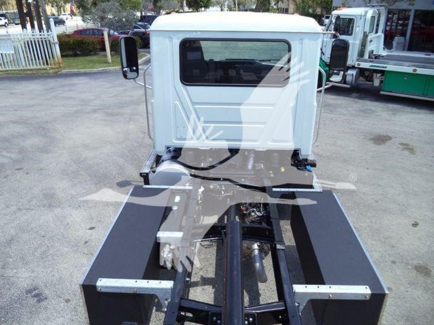 Truck cab and chassis of a 2025 Mack MD6 rollback with a flatbed frame and hydraulic components visible.