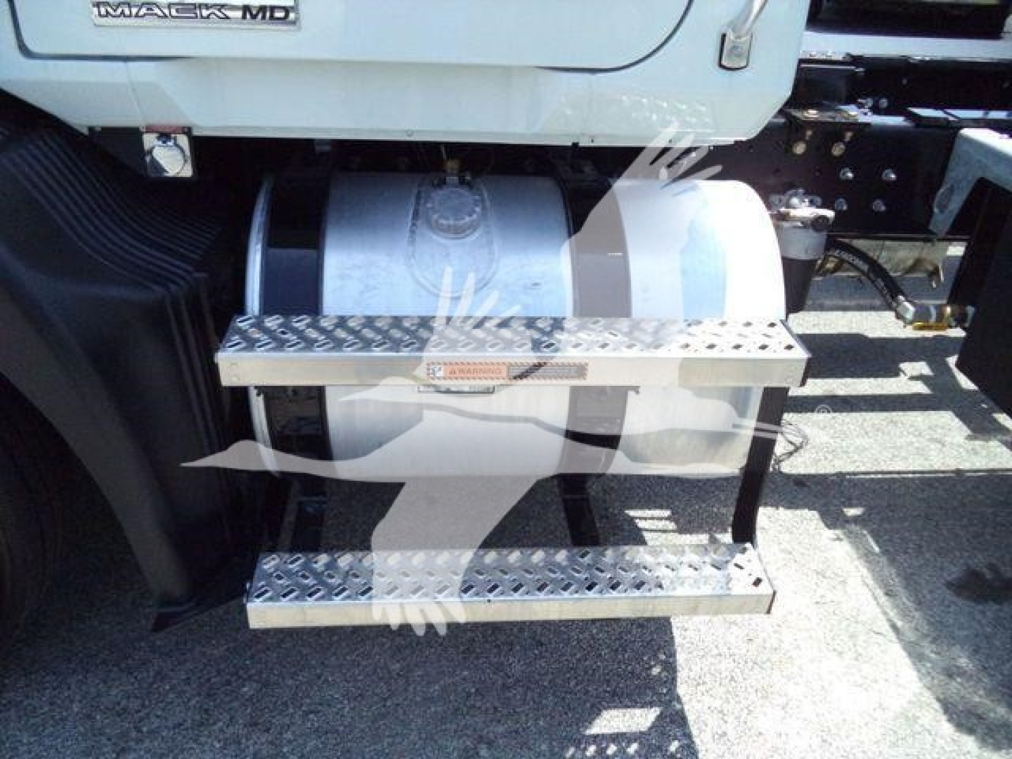 Truck side view showing aluminum diamond-plate steps attached to the Mack MD6 sleeper/cab area and fuel tank behind.
