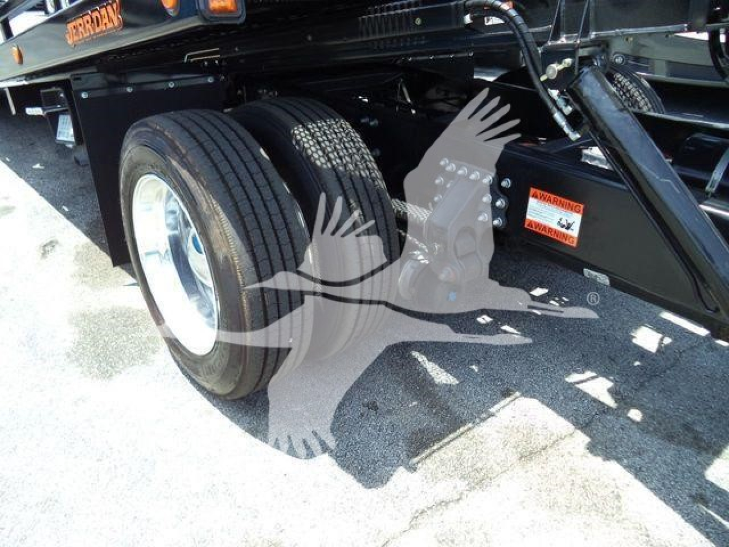Wheel and frame of a Mack MD6 rollback truck showing dual rear tires and undercarriage components.