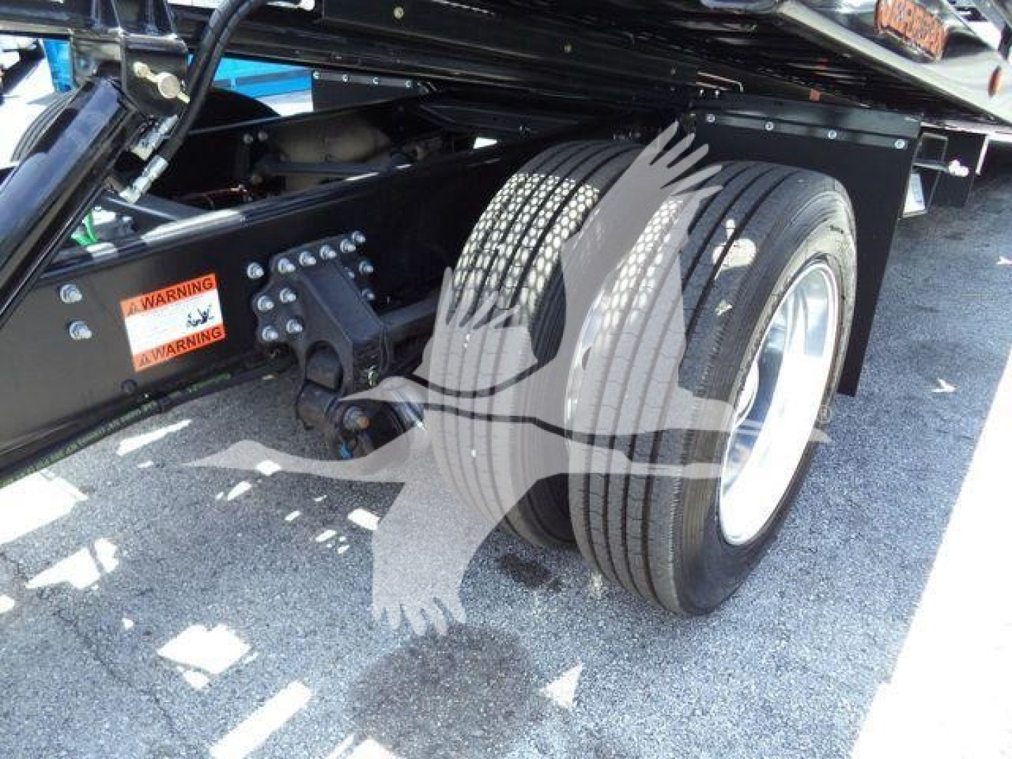 Mack MD6 rear section showing dual rear wheels, suspension brackets, and hydraulic components with warning labels.