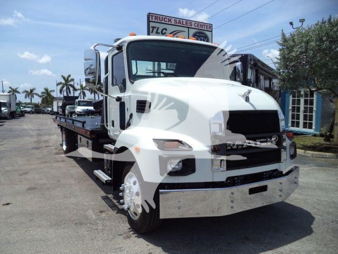 Front view of a white Mack MD6 rollback truck showing flatbed and chrome bumper.
