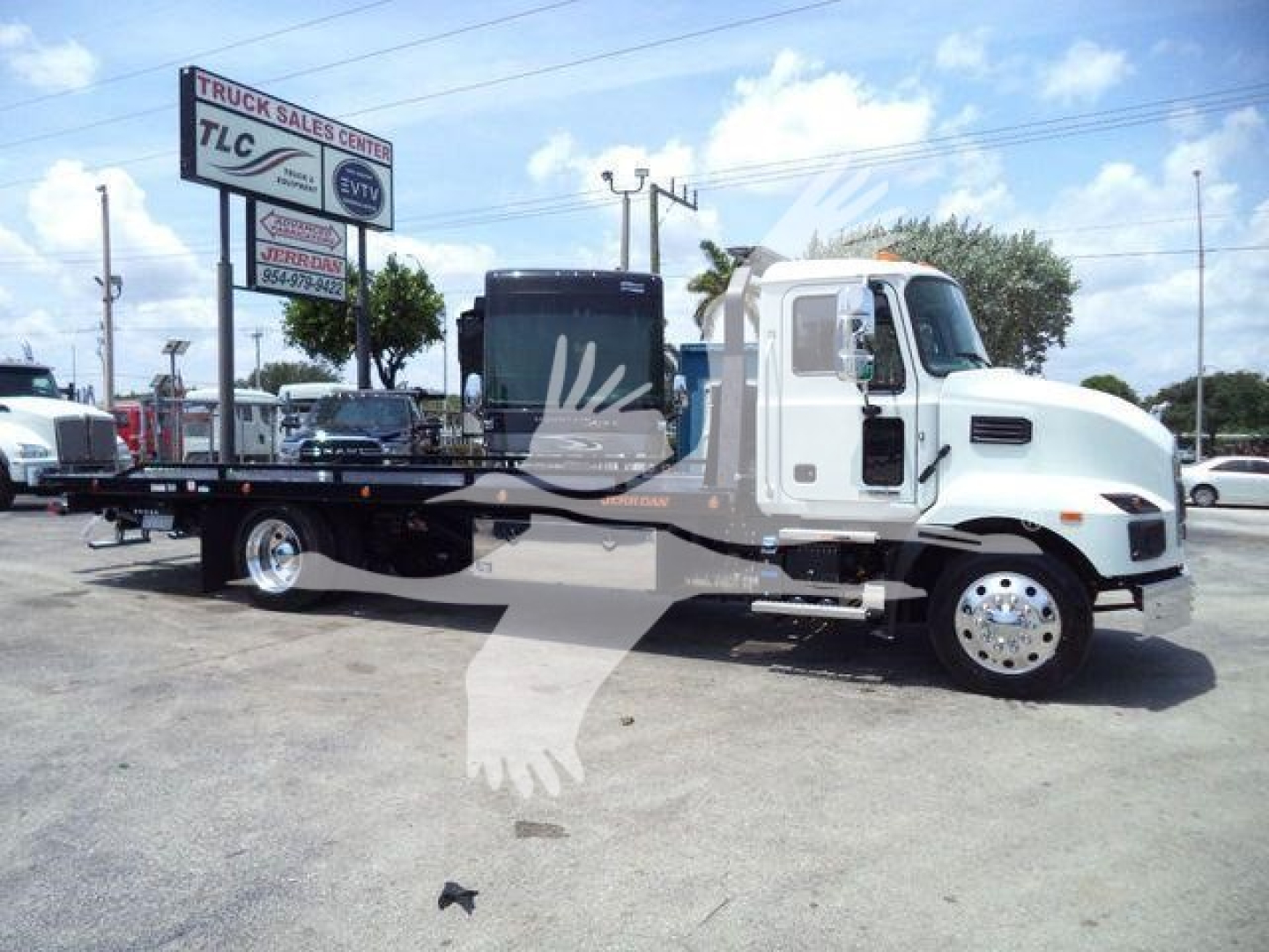 2025 Mack MD6 rollback truck in white and black, side profile view with flatbed, under bright sky.