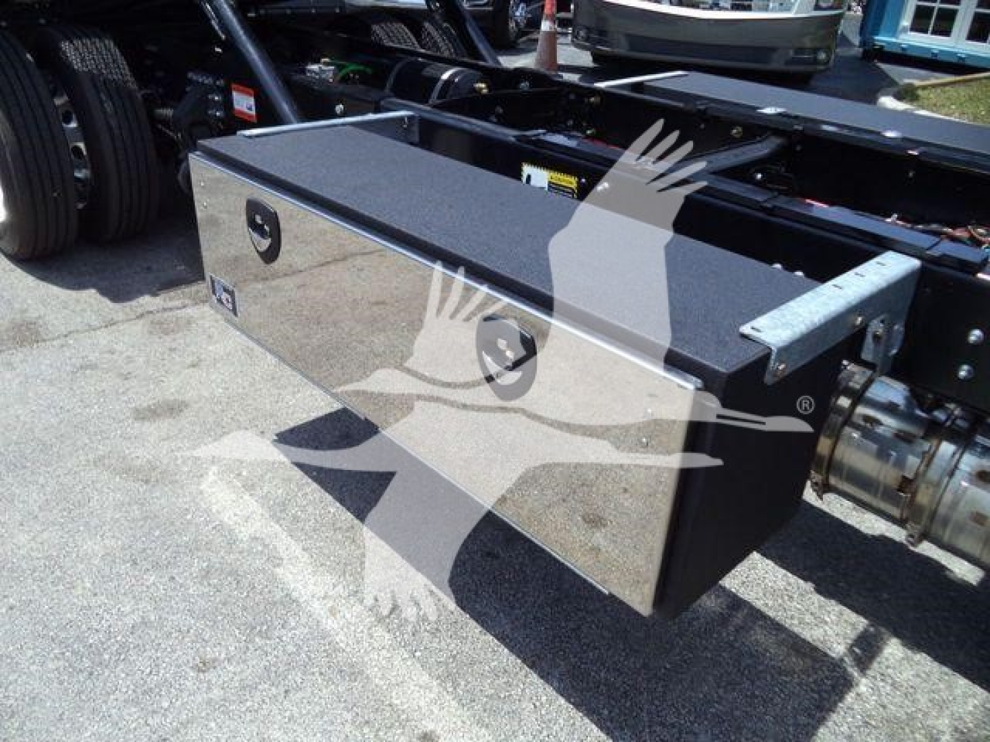 Rectangular metal toolbox mounted on a vehicle chassis, with two circular recessed handles and a textured black top surface.