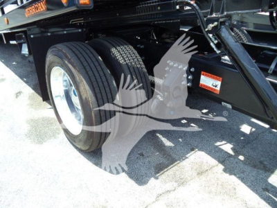 Wheel and frame of a Mack MD6 rollback truck showing dual rear tires and undercarriage components.