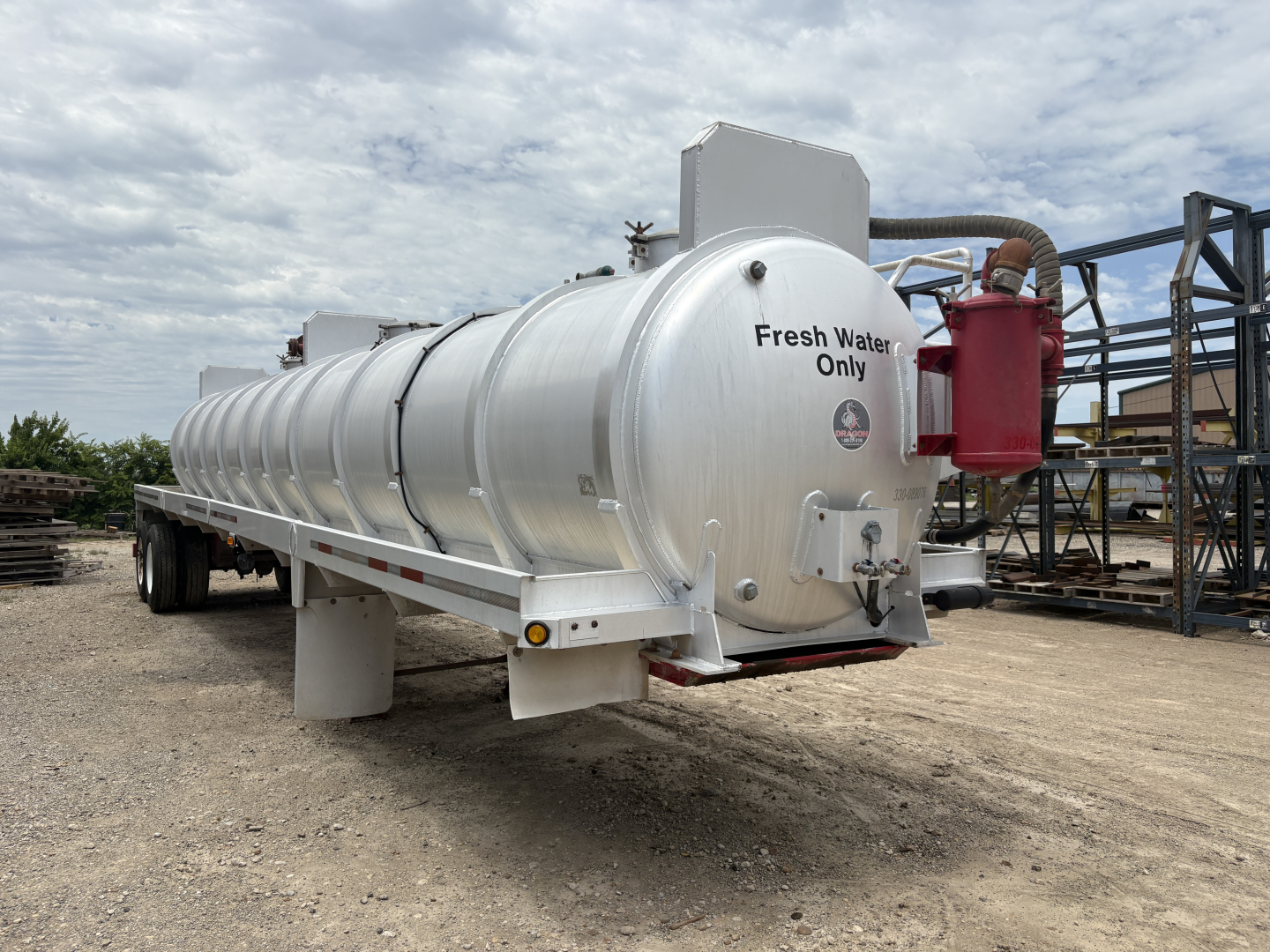 Vacuum trailer tank showing large cylindrical aluminum tank with rear manway and pump system labeled Fresh Water Only; red tank and piping at the back; wheels and support frame visible.